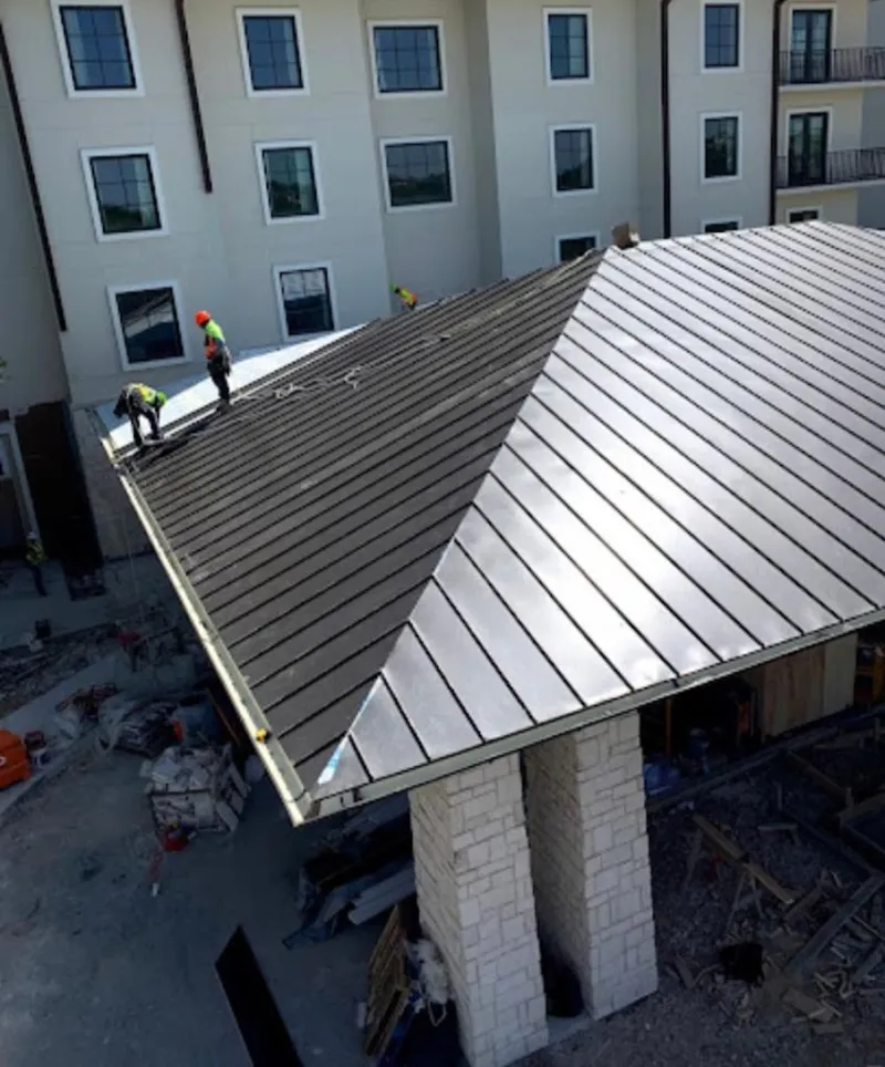Crew installing standing seam metal roof panels on a commercial project in East Palo Alto